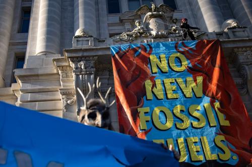 A demonstrator with Extinction Rebellion DC scales the John A. Wilson building and unfurls a banner in Washington, D.C. on April 22, 2022, speaking out against the practices of Washington Gas (Photo by Bryan Olin Dozier/NurPhoto)