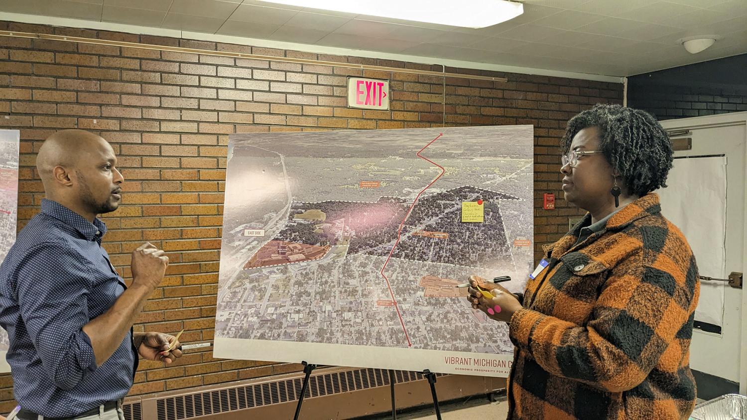 Man and woman conversing in front of a Vibrant Michigan City map