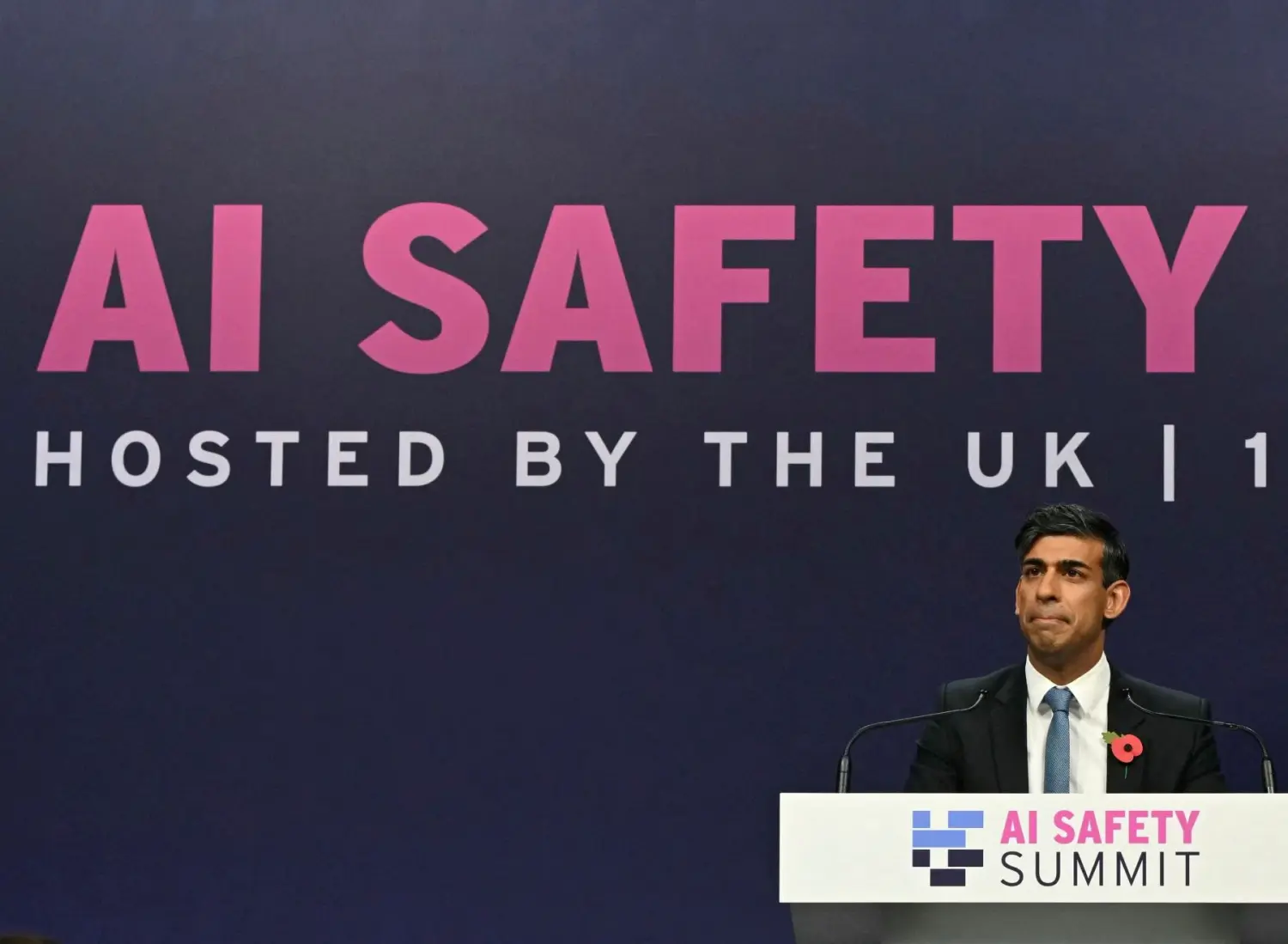 Rishi Sunak stands at the podium in front of a backdrop reading "AI SAFETY."