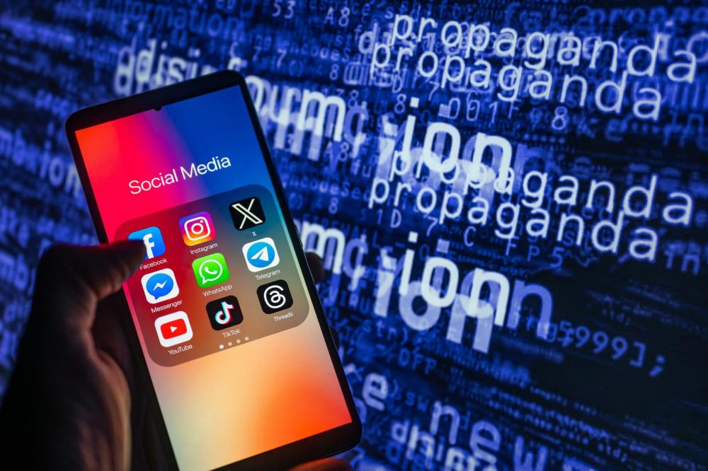 Social media icons logo displayed on a smartphone with disinformation on screen seen in the background, in this photo illustration taken on October 15, 2023.